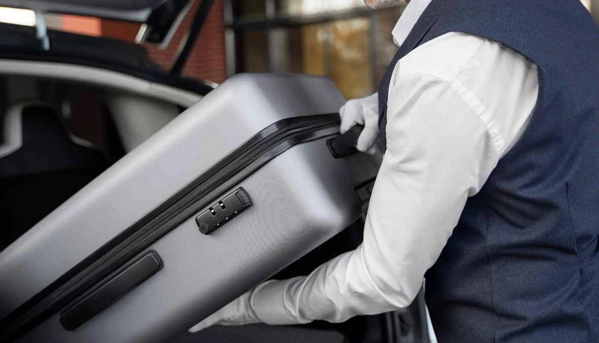 NYC Airports JFK and LGA Service – Efficient Car Transfers 1 Chauffeur placing luggage in the trunk of a limousine, highlighting ZechionRide’s professional airport transfer and luxury transportation services in NYC.