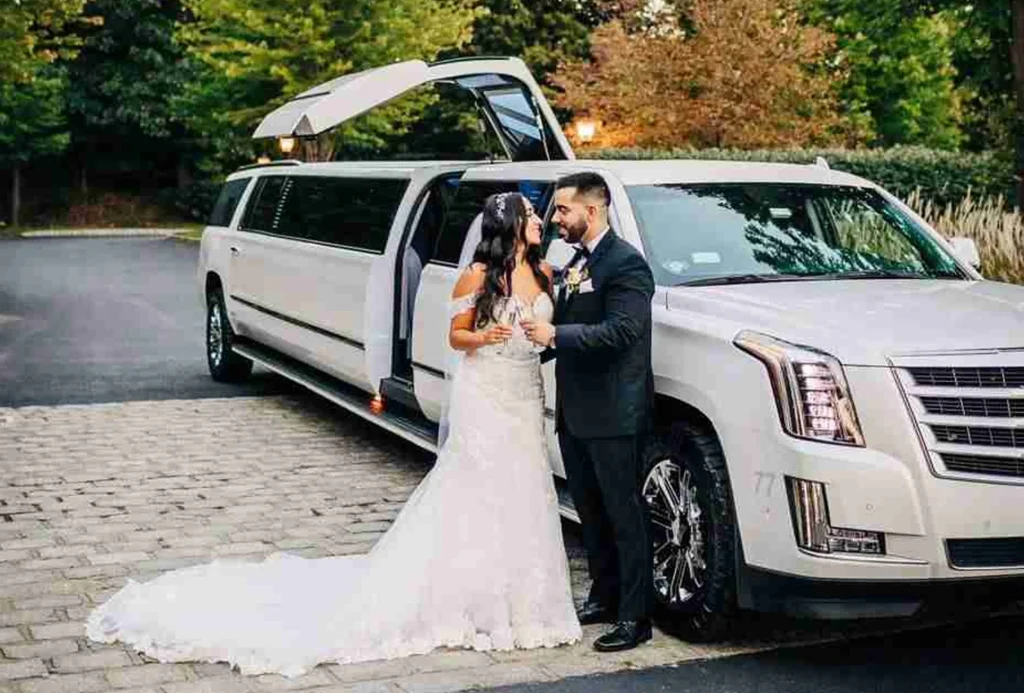 A couple at their wedding, with a stylish limo in the background