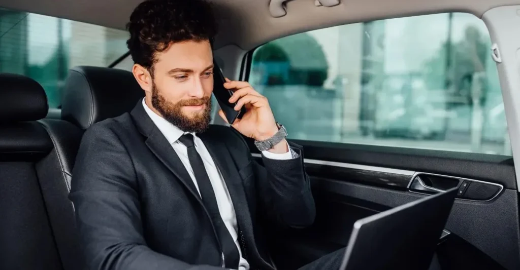 Businessman in a suit using his laptop, & make a limo booking on call for corporate travel