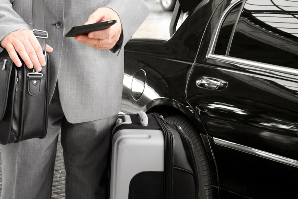 Man in a suit hold a cell phone and suitcase, preparing for corporate travel in a limousine