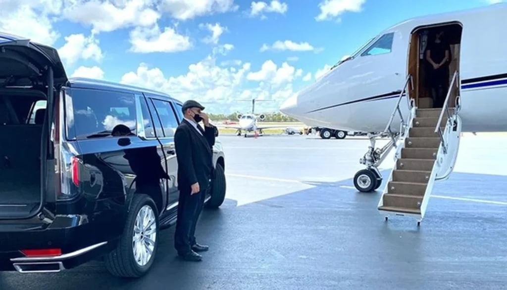 The Benefits of Using a Luxury Limousine for Airport Chauffeur Service When Traveling to LA 2 Man in a suit stands beside a black limousine, with a private jet visible in the background at a Los Angeles airport